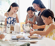 mother is showing her kids how to bake cookies