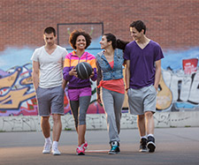Friends are walking together and one friend is holding basketball